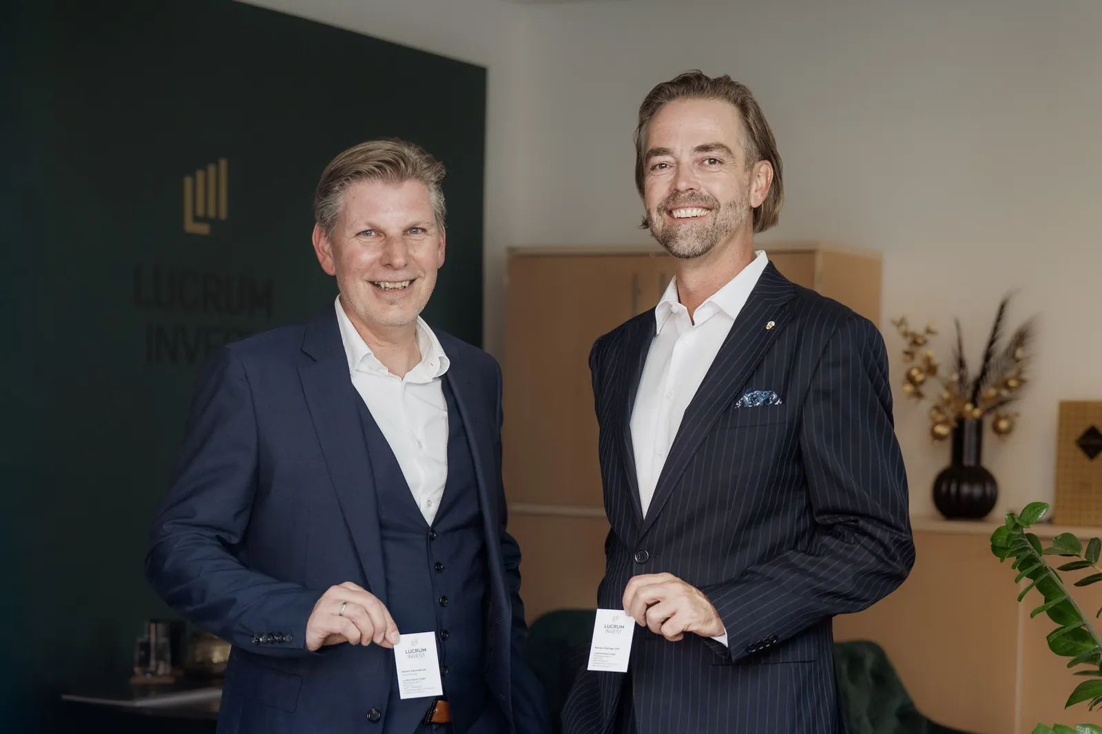 Helmut Hemmelmeir und Roman Zlabinger mit ihren Visitenkarten im Büro von Lucrum Invest