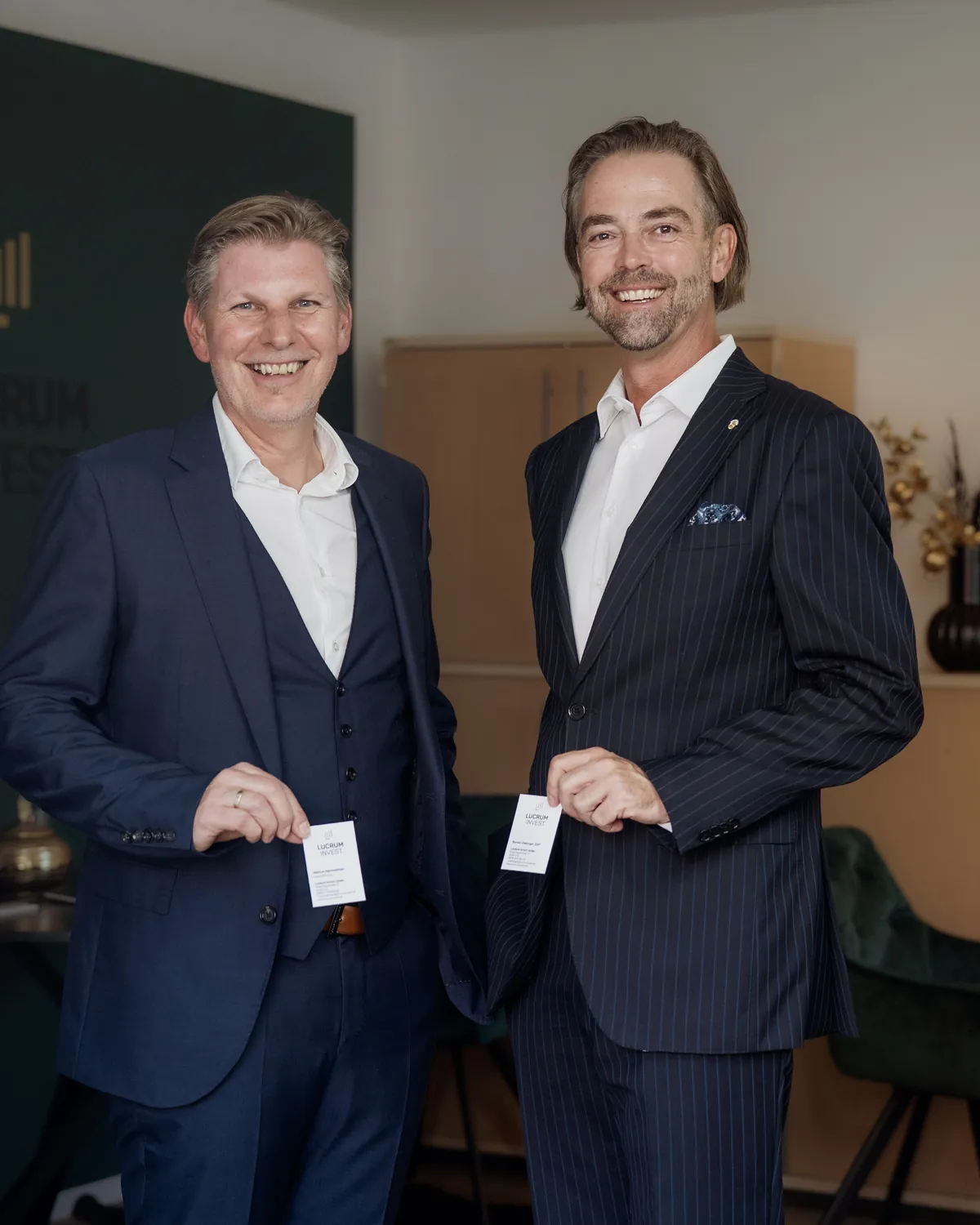 Helmut Hemmelmeir und Roman Zlabinger mit Visitenkarten im Büro von Lucrum Invest